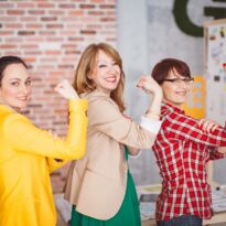 drei Frauen in Business Kleidung zeigen Stärke - spannen Bizeps an