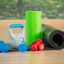 Verschiedene Trainingsgeräte: Igelball, Kettlebell, Hantel, Faszienrolle und Gymnastikmatte