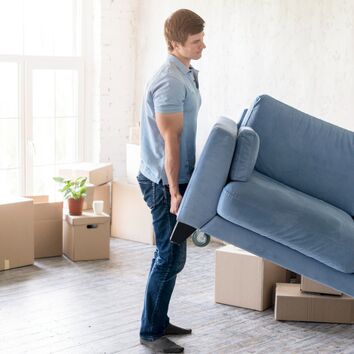 Mann hebt Sofa hoch